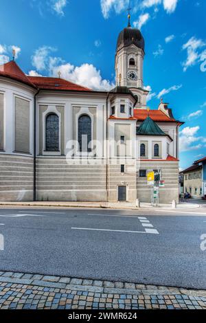 Nesselwang, Germania - 06 luglio 2023: Facciata sud della chiesa di Sant'Andrea con cartelli e vista sulla strada principale contro un cielo blu. Foto Stock