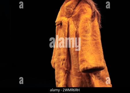 Cappotto in pelliccia da donna di colore giallo brillante su sfondo nero. Look alla moda invernale. Vista laterale Foto Stock