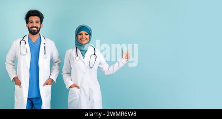 Gioiosi medici musulmani si uniscono in camici da laboratorio puntando da parte lo spazio di copia Foto Stock