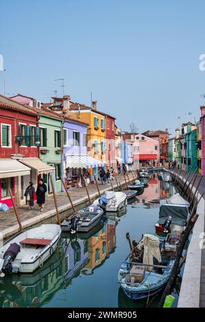 Burano, Italia - 25 febbraio 2023; case colorate lungo il canale principale con piccole barche a Burano Foto Stock