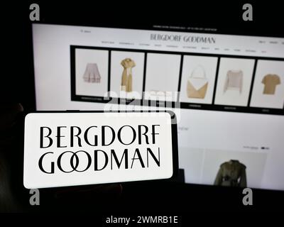 Persona che detiene lo smartphone con il logo della società statunitense di grandi magazzini di lusso Bergdorf Goodman Inc. Davanti al sito Web. Mettere a fuoco il display del telefono. Foto Stock