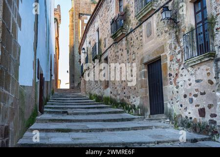 Vicolo stretto e pittoresco con scale e case in pietra nella città di Caceres. Foto Stock