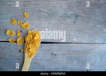 Cucchiaio di legno e fiocchi di mais isolati su bianco. Foto Stock