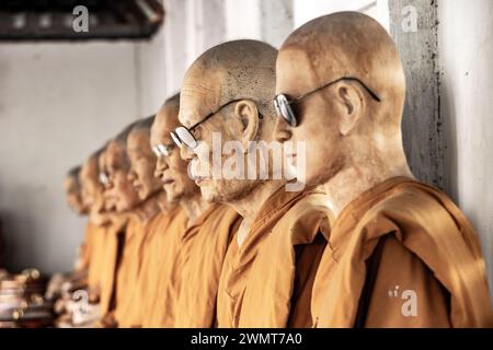 SAMUT SAKHON, THAILANDIA, DEC 03 2023, Una fila di statue di cera di monaci buddisti seduti in un tempio buddista Foto Stock