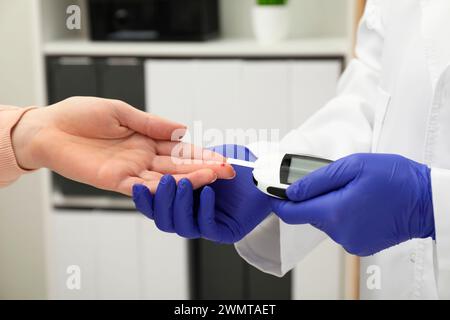 Diabete. Medico che controlla il livello di zucchero nel sangue del paziente con il glucometro in clinica, primo piano Foto Stock