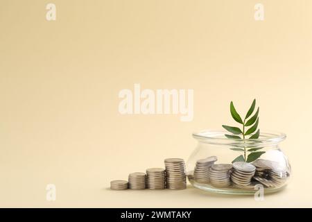 Risparmi finanziari. Monete, ramoscelli e vasetti di vetro su sfondo beige, spazio per il testo Foto Stock