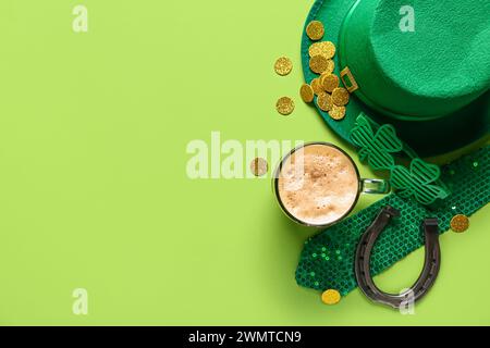 Tazza di birra scura con cappello di leprechaun, occhiali da vista in plastica e ferro di cavallo su sfondo verde. St Giorno di Patrick Foto Stock