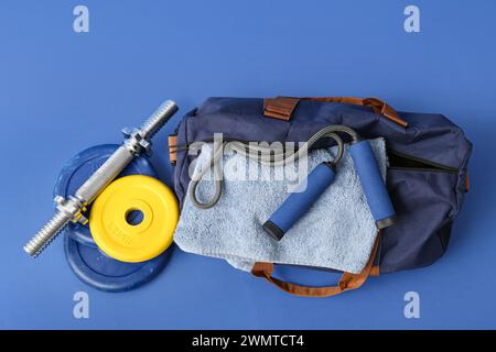 Borsa sportiva con abbigliamento sportivo e manubri su sfondo blu Foto Stock