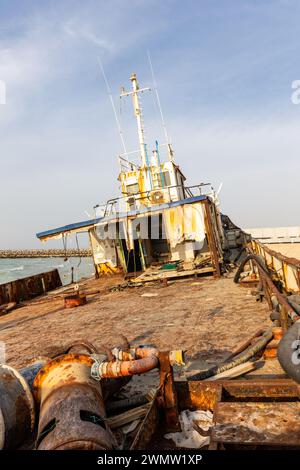 Ponte demolito e arrugginito di una nave da carico con vecchio ponte, albero, antenne e macchinari, lavato a riva sulla spiaggia di al Hamriyah a Umm al Quwain, Emirati Arabi Uniti Foto Stock