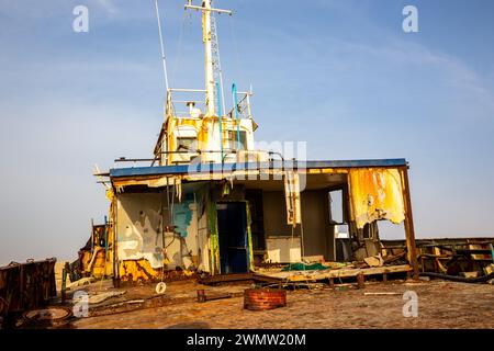 Ponte demolito e arrugginito di una nave da carico con vecchio ponte, albero, antenne e macchinari, lavato a riva sulla spiaggia di al Hamriyah a Umm al Quwain, Emirati Arabi Uniti. Foto Stock