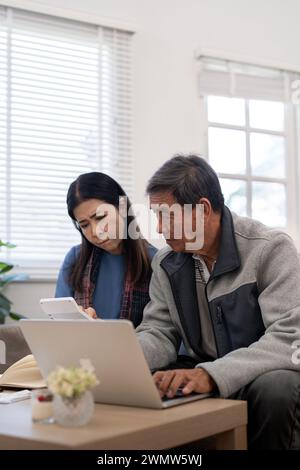 Grave stress asiatico anziani coppia preoccupata per la fattura discutere non pagato debito bancario pagamento carta preoccupazione per problema di denaro Foto Stock