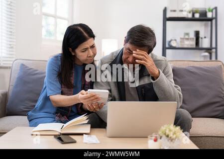 Grave stress asiatico anziani coppia preoccupata per la fattura discutere non pagato debito bancario pagamento carta preoccupazione per problema di denaro Foto Stock