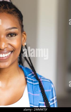 Una giovane donna afro-americana sorride calorosamente, i suoi capelli sono stilizzati in trecce Foto Stock