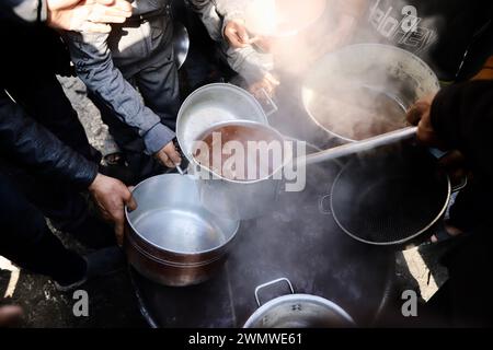 Gaza. 27 febbraio 2024. Le persone ricevono cibo cucinato in un campo profughi nella parte settentrionale della Striscia di Gaza, 27 febbraio 2024. L'osservatore permanente dello Stato palestinese presso le Nazioni Unite, Riyad Mansour, martedì ha detto al Consiglio di sicurezza che Gaza sta attualmente vivendo una carestia, che peggiora ogni giorno a causa della continua "aggressione criminale” da parte di Israele. "Dobbiamo fermarci un momento e riflettere su cosa significhi veramente", Mansour si è rivolto alla riunione del Consiglio di sicurezza sulla protezione dei civili nei conflitti armati. Crediti: Mohammed Ali/Xinhua/Alamy Live News Foto Stock