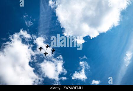 Quattro aerei militari visti dal basso volare su un cielo blu con nuvole Foto Stock