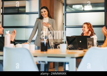 I professionisti aziendali, comprese le donne in affari, collaborano in un ufficio tecnologico. Si impegnano in una discussione vivace, applaudendo i risultati raggiunti. Il lievito Foto Stock