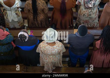 Una donna con un cappello d'argento nella congregazione alla messa domenicale cattolica nella Cattedrale di San Giuseppe, Stone Town, Zanzibar, Tanzania Foto Stock