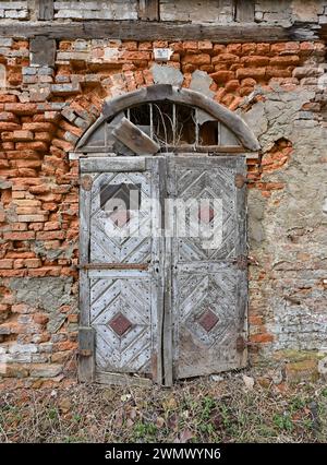 17 febbraio 2024, Brandeburgo, Lübbenau: Un muro di mattoni di una vecchia casa in legno con una porta d'ingresso in legno nella Spreewald. Foto: Patrick Pleul/dpa Foto Stock