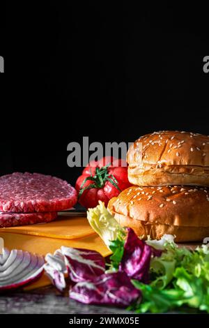 Ingredienti per preparare un hamburger, pane morbido, pomodoro fresco, carne succosa, cipolla croccante e lattuga verde. Scatto verticale Foto Stock