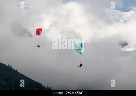 Due parapendio in volo con il Monte bianco (4807 metri) avvolti dalla nebbia sullo sfondo, Chamonix, alta Savoia, Alvernia Rodano Alpes, Francia Foto Stock