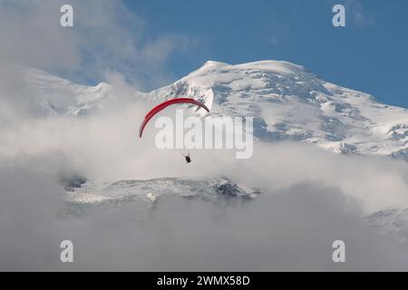 Parapendio tandem con il Monte bianco (4807 metri) avvolto dalla nebbia sullo sfondo in estate, Chamonix, alta Savoia, Francia Foto Stock