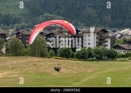 Vista ad alto angolo dei parapendio tandem sul punto di atterraggio nei pressi del centro della città alpina in estate, Chamonix, alta Savoia, Francia Foto Stock