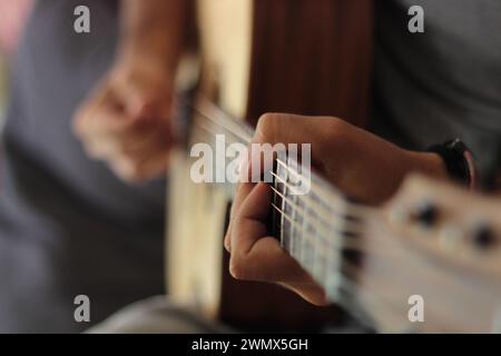 Uno scatto ravvicinato cattura l'abilità emotiva delle mani che suonano una chitarra acustica occidentale. Le dita danzano lungo la lavagna, con melodie decisamente convincenti Foto Stock