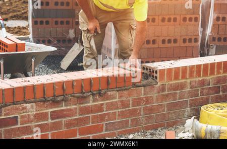 Muratore industriale posa mattoni su impasto cementizio in cantiere Foto Stock