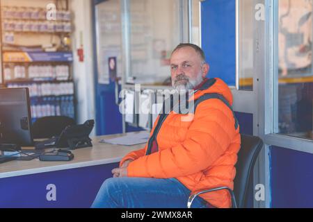 Un uomo che aspetta in garage la manutenzione della sua auto e gli pneumatici invernali montati prima della stagione invernale Foto Stock