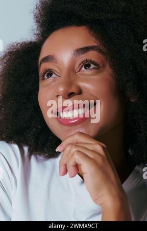 ritratto di una donna afroamericana gioiosa e attraente che posa e guarda lontano, concetto di moda Foto Stock