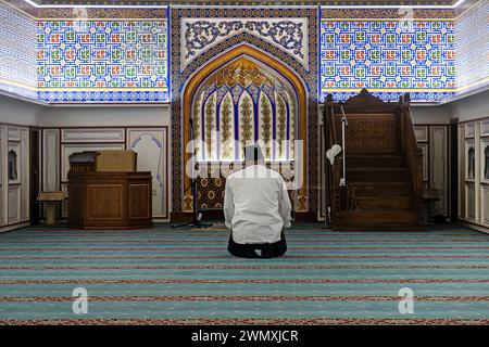 Vista posteriore di un uomo musulmano mentre prega in una moschea. Preghiera all'interno di una bellissima vecchia moschea uzbeka. Foto Stock