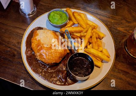 Bistecca di Edimburgo e torta alla birra e una pinta in un pub scozzese con patatine, salsa e piselli moschi Foto Stock