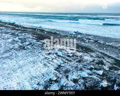 Islanda, costa meridionale, regione di Austurland, laguna di Jökulsárlón, spiaggia di diamanti o di diamanti, iceberg di Breiðamerkurjökull sulla spiaggia di sabbia vulcanica nera (vista aerea) Foto Stock
