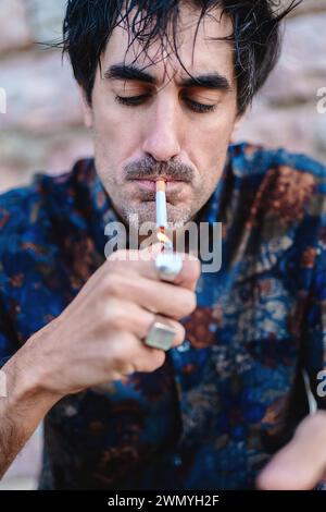 Primo piano di un uomo che accende una sigaretta, concentrandosi sulla partita illuminata e sul suo atto di fumo Foto Stock