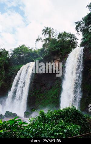 Una vista mozzafiato delle cascate dell'Iguazú con cascate circondate da vegetazione tropicale sotto un cielo azzurro. Foto Stock