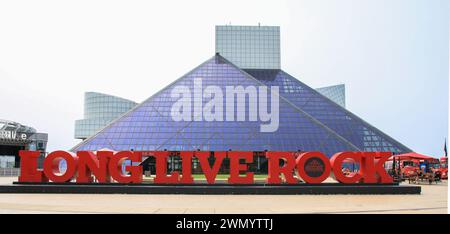 Cleveland, Ohio, Stati Uniti - 2 agosto 2023: L'audace cartello rosso di Long Live Rock si erge di fronte a un suggestivo edificio piramidale di vetro blu, Symboliz Foto Stock