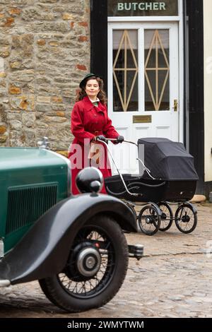 Grassington, Yorkshire, Regno Unito. 28 febbraio 2024. Le riprese della location iniziano per la quinta serie del popolare programma di Channel 5 e della PBS All Creatures Great & Small. Il cast e la troupe sono stati avvistati per le strade della piccola cittadina di Grassington, nello Yorkshire Dales, che viene convertita, due volte l'anno, nella città immaginaria di Darrowby. Nella foto Rachel Shenton (Helen Herriot) filma una scena. Credito: Tom Holmes Photography / Alamy Live News). Foto Stock