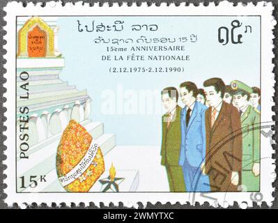Francobollo cancellato stampato dal Laos, che mostra commemorazione, 15 ° anniversario della Repubblica Popolare, circa 1990. Foto Stock