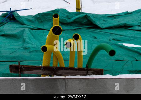 Tubi in plastica gialli e verdi nel cantiere dell'abitazione. Copertura verde sullo sfondo. Foto Stock
