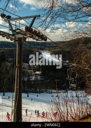 A Sigulda si dispiega una pittoresca scena mentre gli sciatori scendono le piste innevate sullo sfondo del fiume Gauja, visibile dalla seggiovia, aggiungendo Foto Stock
