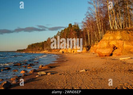 Nel mezzo della tranquilla bellezza di Veczemju Klintis, Latvija, l'ora d'oro del tramonto bagna la spiaggia rocciosa in un caldo bagliore, offrendo un momento di serenità Foto Stock