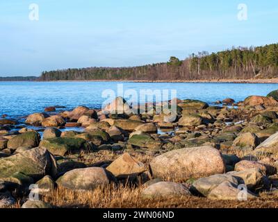 Nella quiete del crepuscolo, Veczemju Klintis trasuda un fascino sereno, mentre la costa rocciosa della spiaggia diventa un rifugio tranquillo immerso nel caldo bagliore del tramonto. Foto Stock