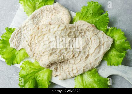 Trippa di bestiame crudo pulita e lavata sul tagliere su un tavolo rustico scuro Foto Stock