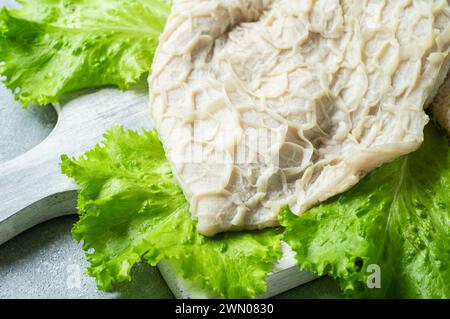 Trippa di bestiame crudo pulita e lavata sul tagliere su un tavolo rustico scuro Foto Stock