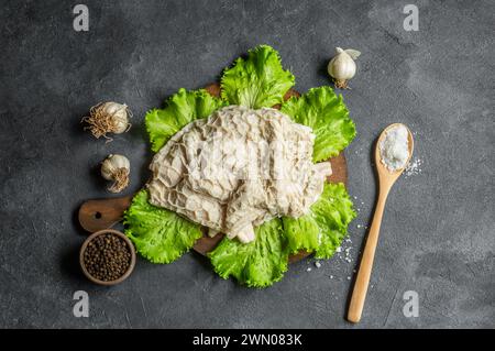 Trippa di bestiame crudo pulita e lavata sul tagliere su un tavolo rustico scuro Foto Stock