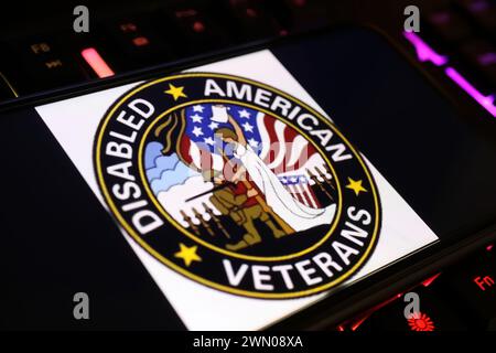 Viersen, Germania - 9 gennaio. 2024: Schermo dello smartphone con logo dell'organizzazione dei veterani americani disabilitata DAV sulla tastiera del computer Foto Stock