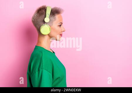 Ritratto del profilo di una bella persona positiva goditi la musica con le cuffie e lo spazio vuoto isolato su sfondo rosa Foto Stock