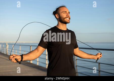 l'uomo in forma salta la corda saltando su un molo sul mare all'esterno Foto Stock