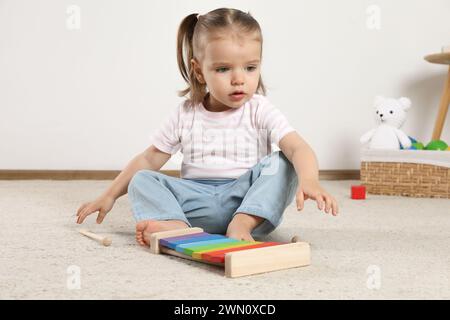 Una bambina carina con xilofono e bacchette di batteria a casa Foto Stock