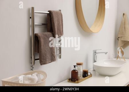 Portasciugamani riscaldato con asciugamani marroni in bagno Foto Stock